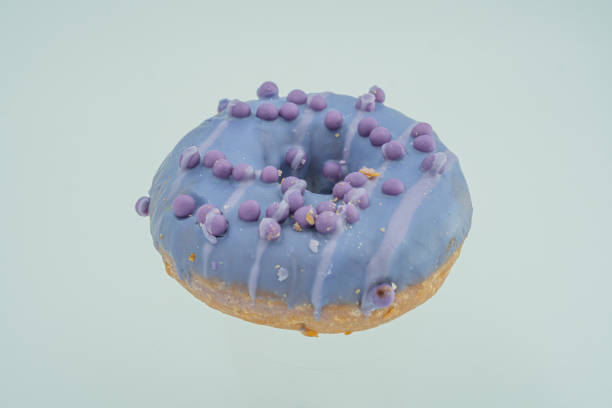 istock A single, freshly made blue-glazed doughnut with purple sprinkles sits on a light gray surface 2197088578