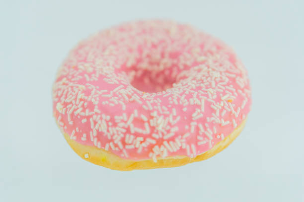 istock A single pink-glazed doughnut with white sprinkles, showcasing a textured surface and light interior against a plain background 2197088583