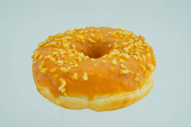 istock Image of a single, glossy doughnut with yellow sprinkles on a light background 2197088728