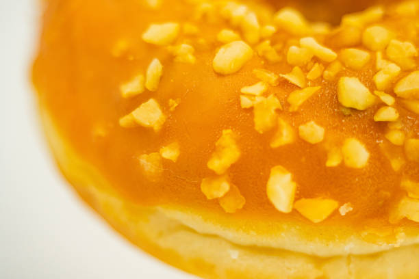 Close-up image of a golden-brown glazed doughnut with nutseed-like granules, centered against a neutral background Realistic style photography showcasing color and texture for culinary or advertisi