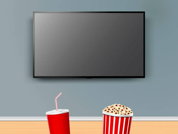 istock Watching TV with red paper cola cup and striped box with popcorn. Movie night at home with popcorn and cola 2197099664