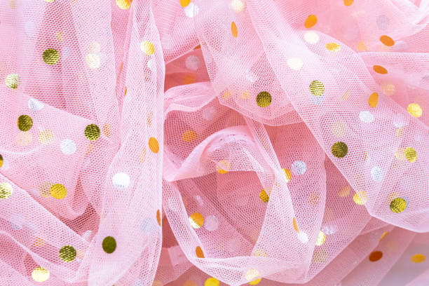Pink tulle fabric adorned with golden polka dots creates a delicate and elegant backdrop