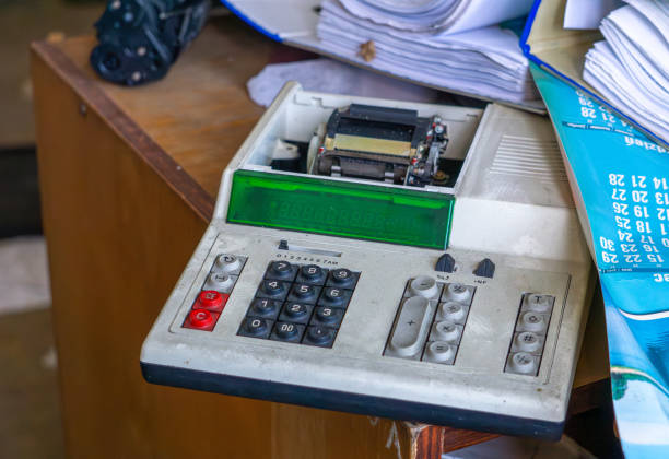 vintage old calculator with printer on a desk in an abandoned and devastated old manufacturing plant. electronic classics
