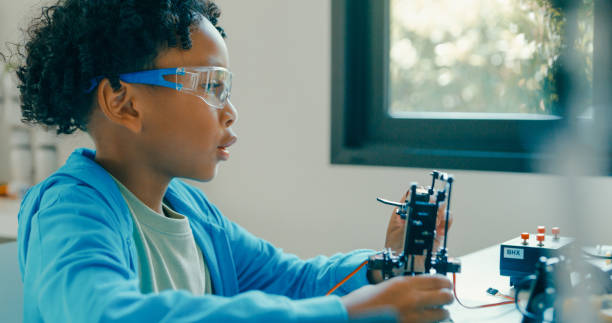 istock Young African-American boy explores robotics and engineering at home, demonstrating enthusiasm and focus during an online educational session. STEM Education robotics courses online. 2197102653