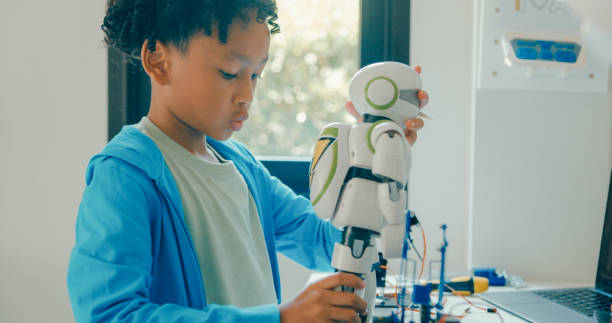 istock Young African-American boy meticulously assembles and adjusts robotic arm, showcasing his engagement with STEM learning in home workshop. STEM Education robotics courses online. 2197102685
