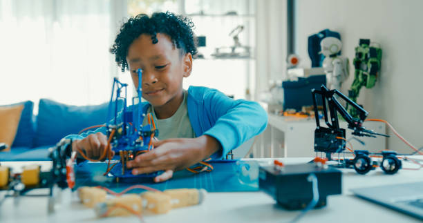 istock Young African-American boy explains robotics project, showcasing creation while discussing technology and innovation from home. STEM Education robotics courses online. 2197102696