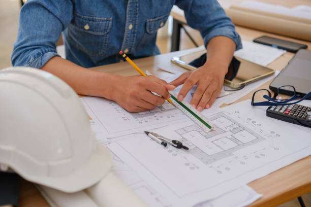 istock Architect and engineer drawing blueprints with a pencil and ruler at a work desk 2197104762