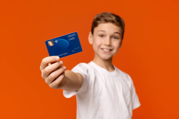 istock Smiling boy showing credit card at camera 2197107512