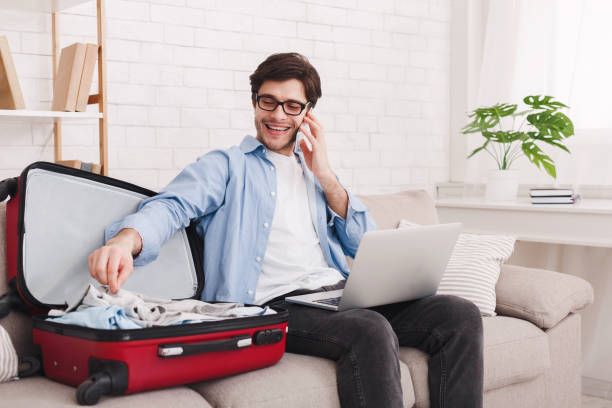 istock Prepare for travel. Man talking on phone and packing clothes 2197108450