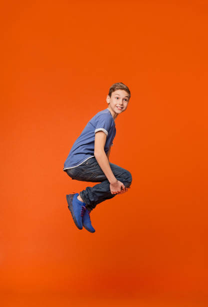 istock Emotional boy jumping in bomb style on orange 2197112048