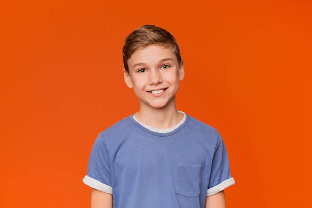 istock Portrait of young boy on orange background 2197112303
