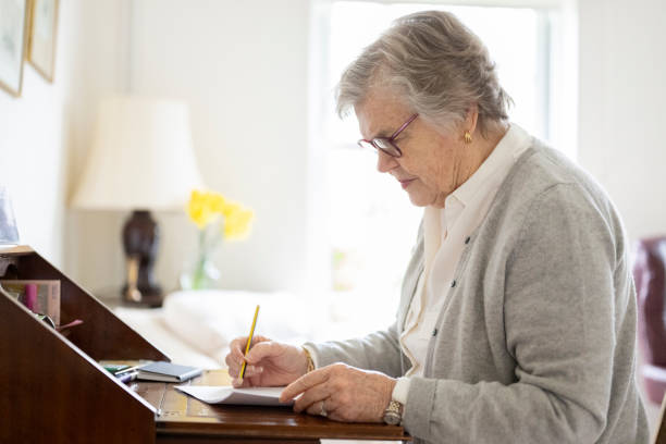 istock Senior woman writing in pencil on document 2197117203