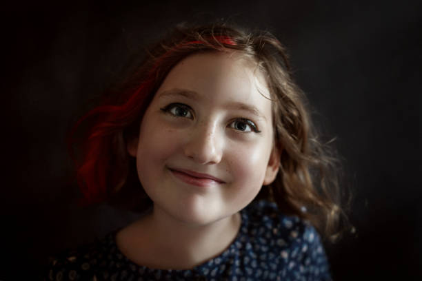 istock Girl smiles with joyful expression. Portrait against dark background in studio 2197117221