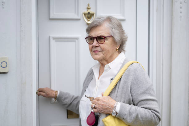 istock Senior woman leaving her house, locking front door 2197117228