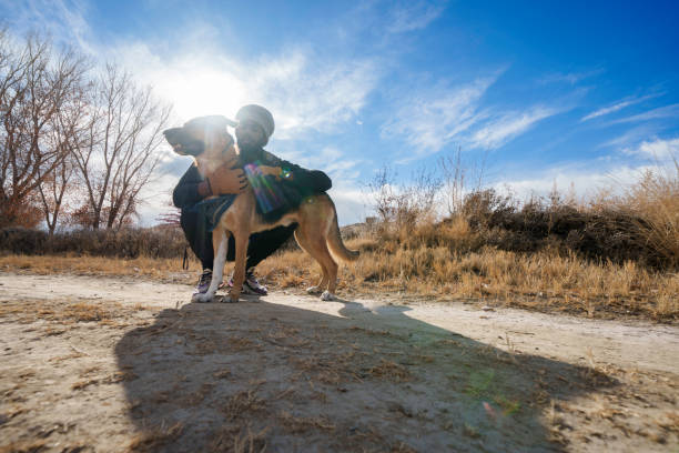 Rear view of a young man hug his dog,black labrador