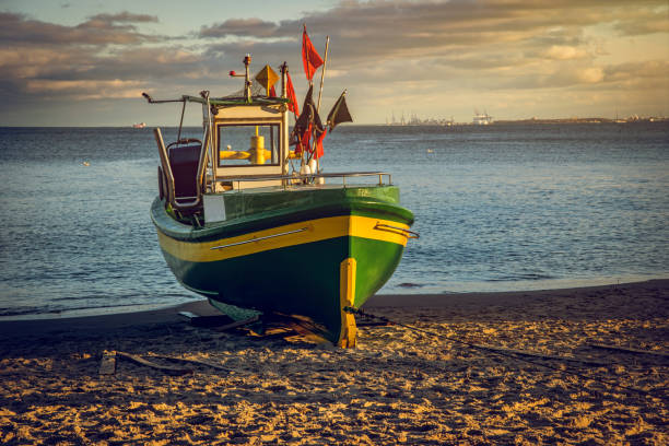 Old fisher boat on the sandy beach. Beautiful sunset seascape on the Baltic Sea coast