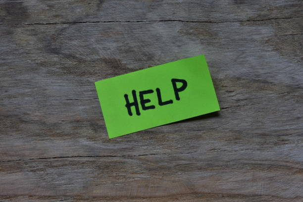 Message help on green sticky note on wooden board textured background. Black marker wrote word help on note paper.
