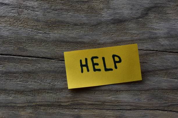 istock Message help on yellow sticky note on wooden board textured background. Black marker wrote word help on note paper. 2197121428