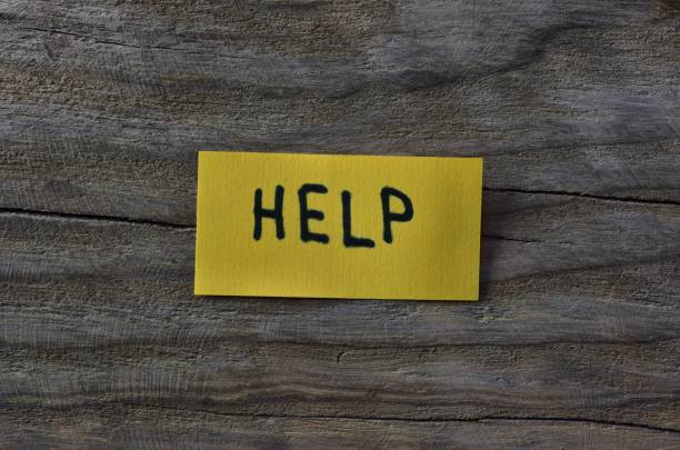 istock Message help on yellow sticky note on wooden board textured background. Black marker wrote word help on note paper. 2197121432