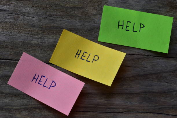 istock Message help on pink green and yellow sticky note on wooden board textured background. A pen wrote word help on note papers. 2197121701