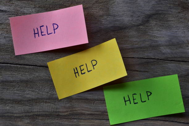 istock Message help on pink green and yellow sticky note on wooden board textured background. A pen wrote word help on note papers. 2197122411