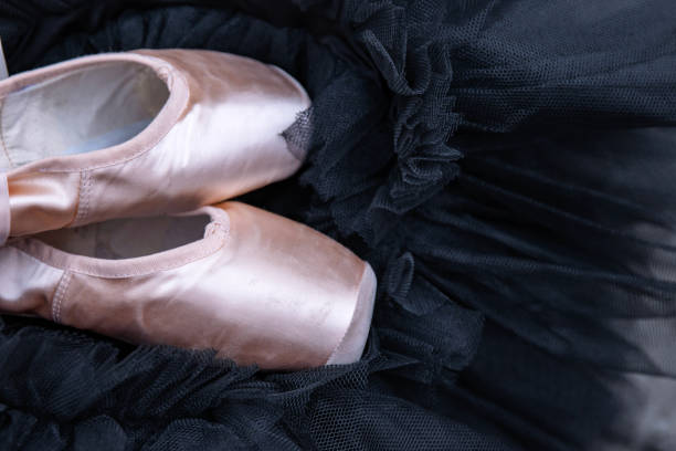 Close-up of a female ballet dancer's feet, showcasing elegant pointe work in soft lighting. The dancer wears pale pink pointe shoes and tights, highlighting her skill and dedication to the art of ballet.