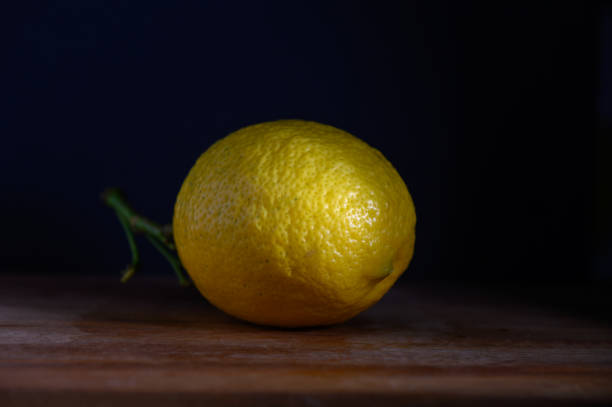 istock Fresh yellow lemon resting on a wooden surface against a dark background 2197123523