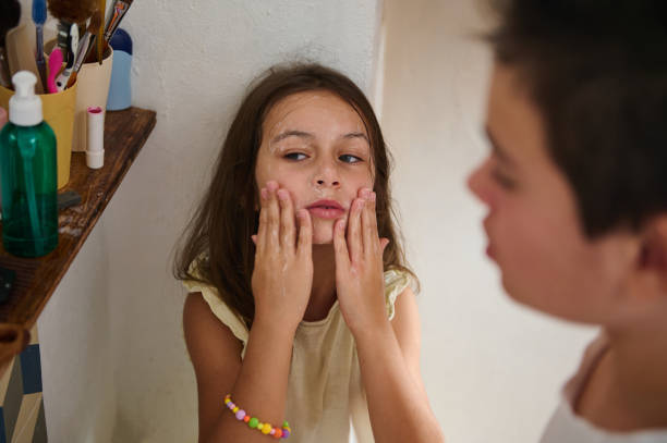 istock Young girl applying cream to her face in a bathroom setting 2197125534