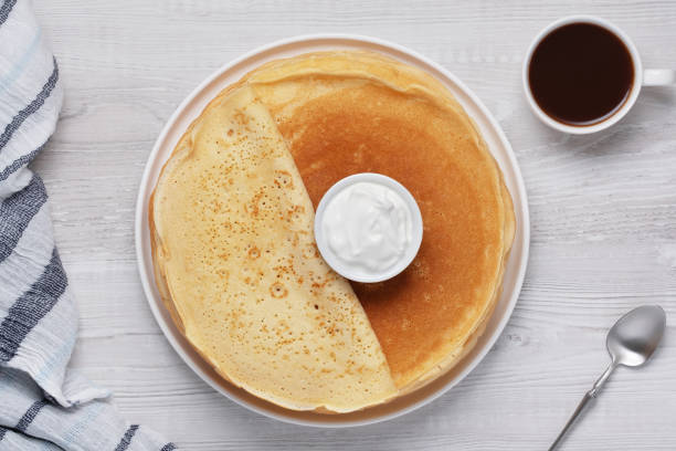 Breakfast with pancakes, cream, and coffee on a wooden table during the morning