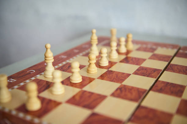 Close-up view of a chessboard displaying neatly arranged wooden chess pieces, suggesting strategy and focus on gameplay. The smooth textures and precise arrangement highlight a classic board game scene.