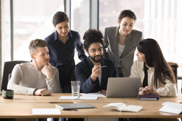istock Friendly engaged young mentor man training new diverse employees 2197128776