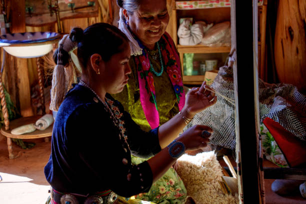 istock Traditional Elderly Navajo Woman Working to Make an Authentic Blanket on a Loom, Teaching Her Granddaughter and Spending Quality Time in a Traditional Navajo Hogan in Monument Valley Southern Utah, Northern Arizona 2197130161