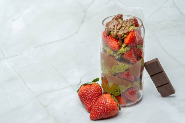 viralowy kubek truskawkowy z czekolady dubai z kunafą, pastą pistacjową, tahini, mleczną czekoladą i świeżymi truskawkami. udekorowane truskawkami i kawałkiem tabliczki czekolady. kopiuj miejsce na tekst. - czekolada dubajska obrazy zdjęcia i obrazy z banku zdjęć