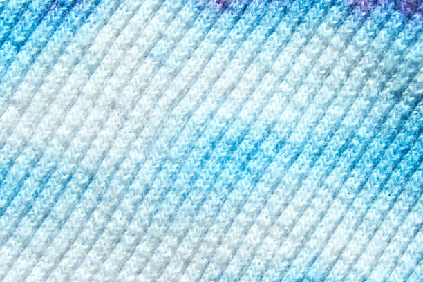 Close up texture of blue and white knitted fabric with gradient patterns.