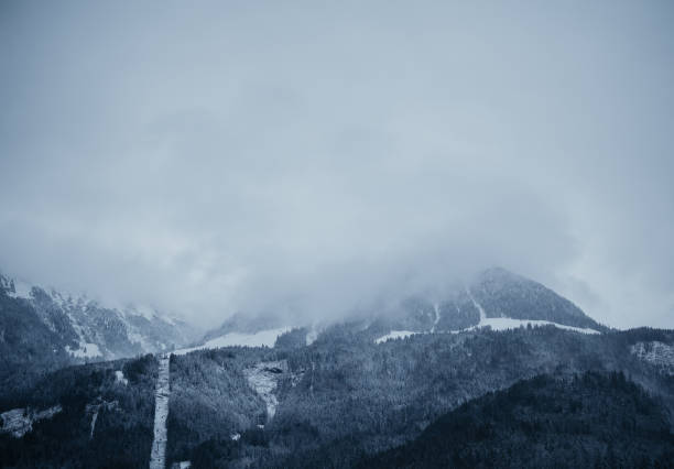 Clouds drift over snow-covered mountains in a serene winter landscape.