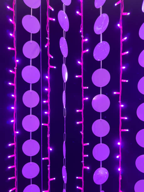 Purple string lights and round hanging decorations create a vibrant, festive ambiance with glowing pink and violet tones against a dark background