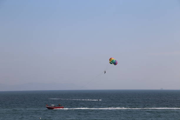 A colorful parachute is flying in the sky above a body of water. The scene is serene and peaceful, with the parachute adding a sense of excitement and adventure to the otherwise calm ocean