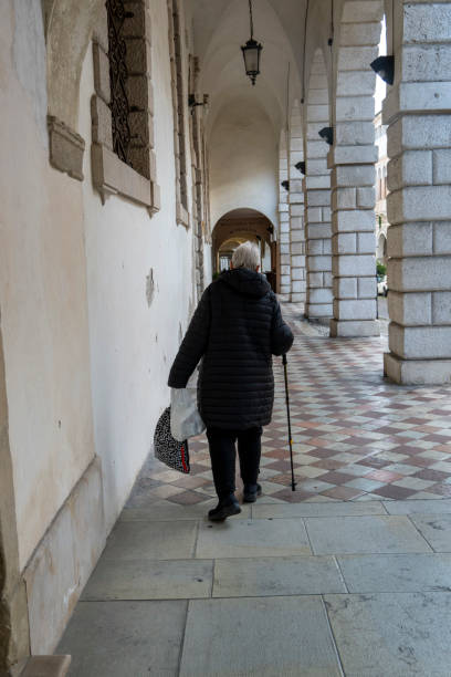 istock Senior citizen walks down an Italianstreet with her walking stick 2197159406