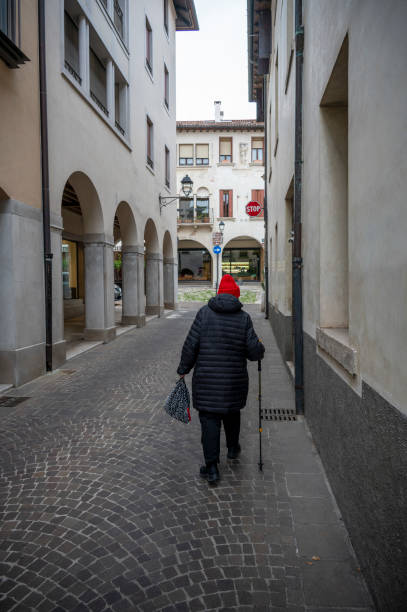 istock Senior citizen walks down an Italian street with her walking stick 2197159421