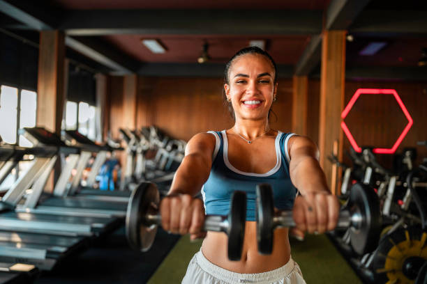 istock Smiling Hispanic Female Lifting Weights In Gym 2197159448