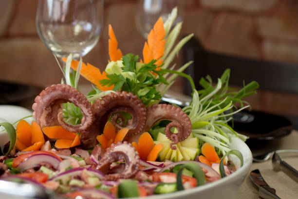 This vibrant dish features marinated octopus paired with fresh vegetables like cucumber, carrot, and red onion. The tender texture of the octopus tentacles contrasts beautifully with the crunchy veggies, offering a refreshing, slightly spicy salad perfect for summer. A colorful, appetizing platter designed to showcase the natural freshness of the ingredients.