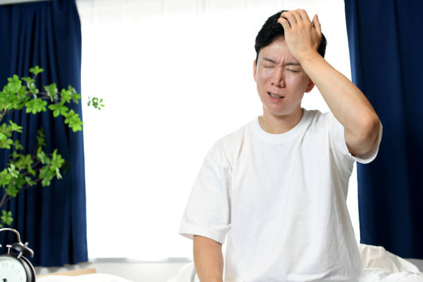 ベッドに頭を抱えている若いアジア人男性 - うつ病 日本人 ストックフォトと画像