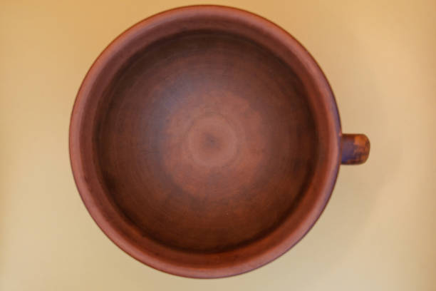 Top view of an empty rustic wooden mug placed on a yellow background, showcasing its natural texture and minimalist design in a simple and aesthetic composition