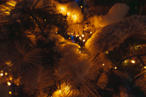 Christmas tree adorned with red and gold ornaments, glowing fairy lights, and snow-covered branches. A festive and cozy winter scene with a warm holiday atmosphere