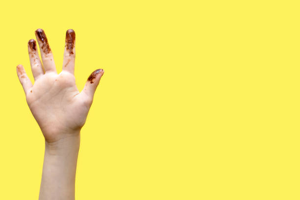Children's hands smeared in chocolate on a yellow background Children's hands smeared in chocolate on a yellow background. The concept of love for sweets and free space for text between hands chocolate fingers stock pictures, royalty-free photos & images