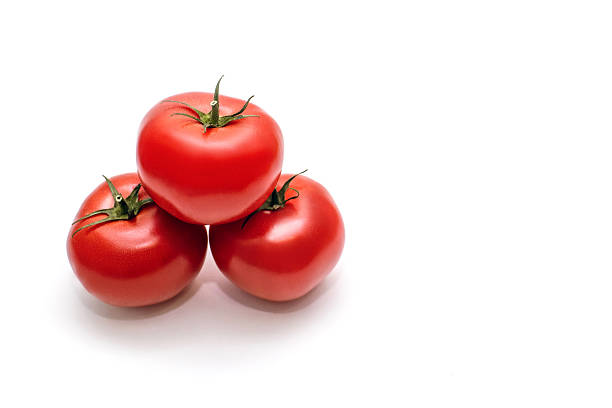 Three juicy tomatoes lie on a white isolated background. Red tomatoes with green stems, top view. Vegetables full of vitamins in the form of fresh juicy tomatoes. Free space for text