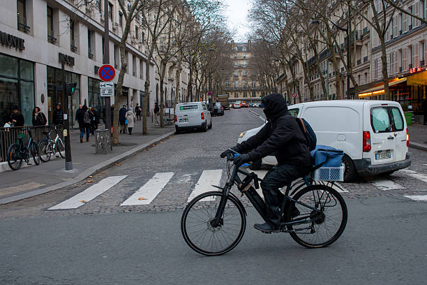 A bundled-up bicycle delivery man on a Parisian street in winter. Paris. Spain. December 9, 2024.