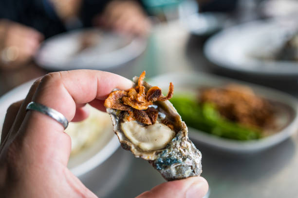 istock Fresh oyster in shell on hand that topping with fried shallot 2197176347