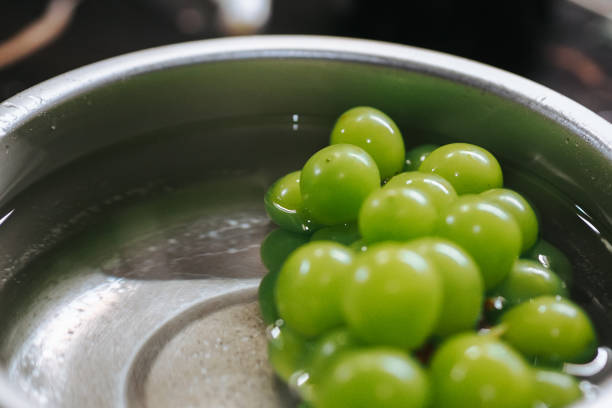 a sprig of shine muscat grapes is washed in a container
