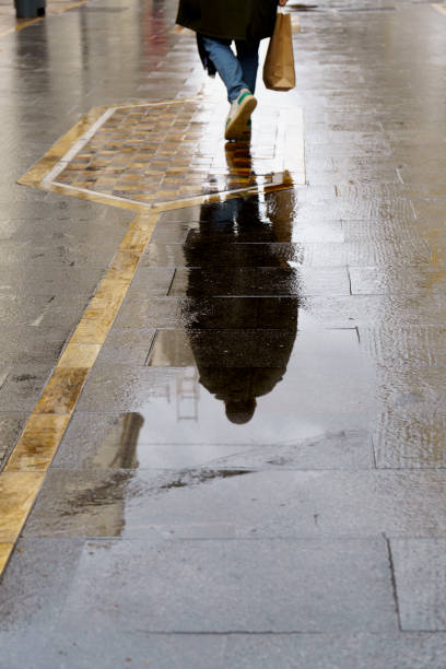 istock woman reflected in a puddle on a rainy day 2197177661
